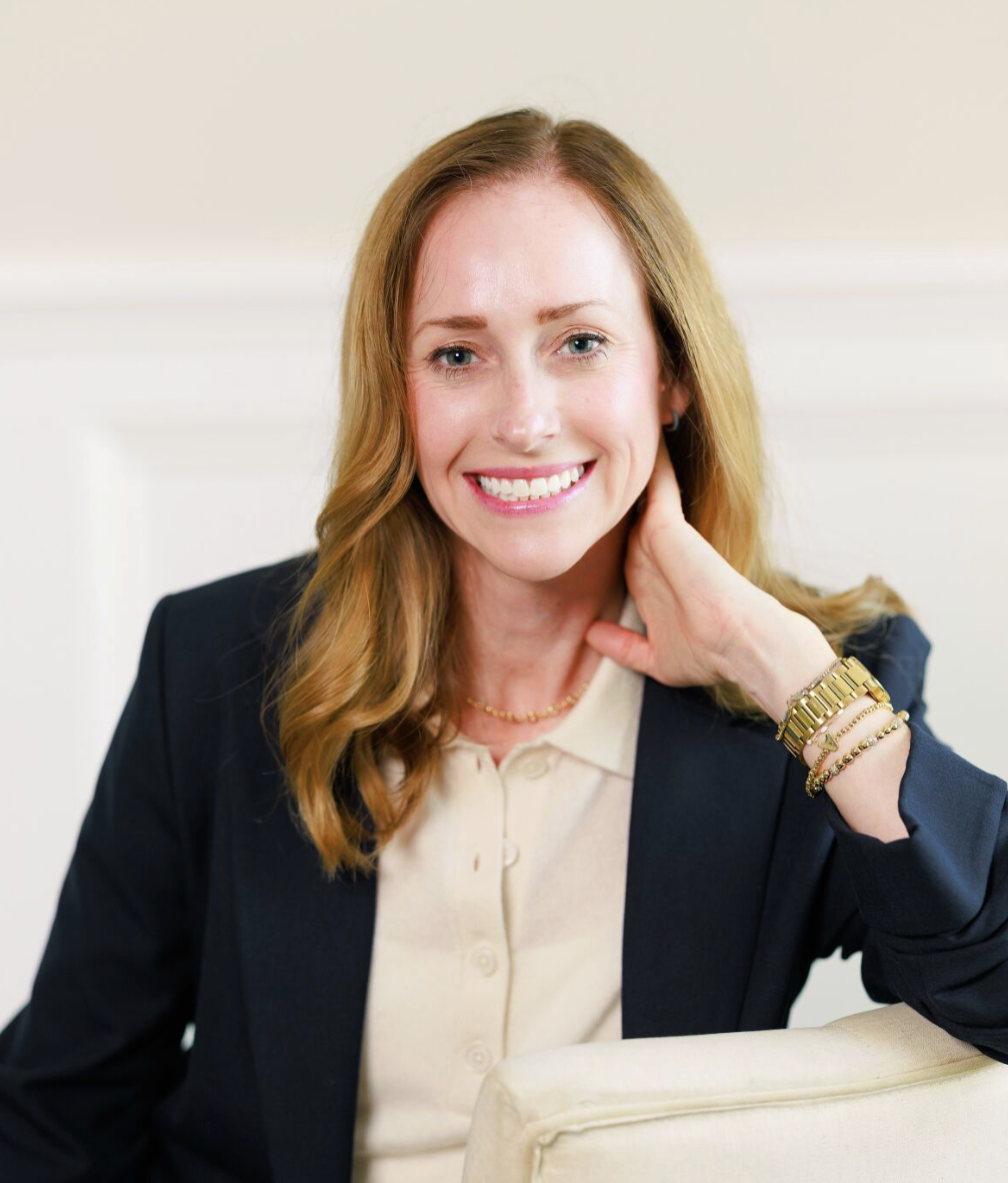 A woman sitting on a cream chair smiling